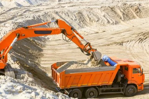 Work of the excavator at quarry. Loading sand into a dump truck. Stock Photos