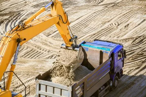 Work of the excavator at quarry. Loading sand into a dump truck. Stock Photos