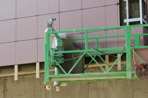 Work with green front two suspended cradle without workers on a newly built high Stock Photos
