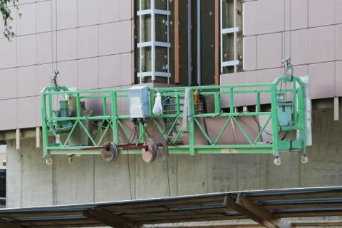 Work with green front two suspended cradle without workers on a newly built high Stock Photos