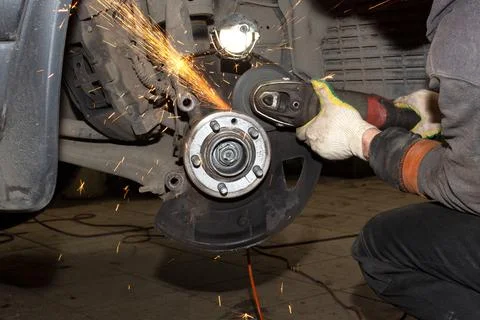 Work with a grinder. Sparks fly in different directions. A mechanic repairs a Stock Photos