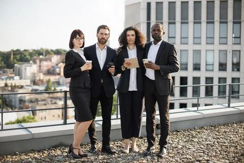 Work group posing on camera with coffee and gadgets outdoors Stock Photos