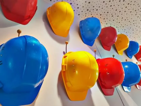Work helmets of different colors hang on hooks on the wall.. Stock Photos