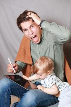 Work from home. This is a developer working on a tablet computer with childre Stock Photos