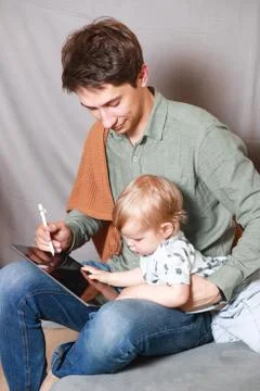 Work from home. This is a developer working on a tablet computer with childre Stock Photos