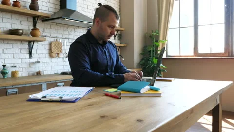 Work at home. A man during quarantine works with a laptop in the kitchen. Stock Footage 133445276
