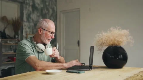 Work from home. An old man in his 60s works on a computer. He is a freelancer. Video stock 228878719