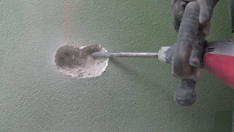 Work of a jackhammer. Drilling hole in concrete wall. Close Up Video stock 177375283
