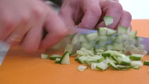 Work in the kitchen. A cook cuts a cucumber with a knife. Stock Footage 229844861