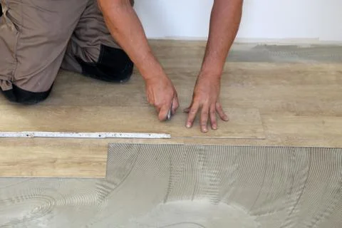 Work on laying flooring. Worker installing new vinyl tile floor. Stock Photos