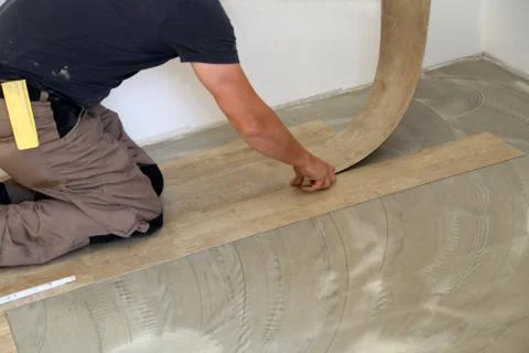 Work on laying flooring. Worker installing new vinyl tile floor. Stock Photos