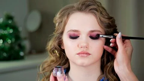 Work of a makeup artist. Applying shadows to the eyelid of the model's eye. Stock Photos