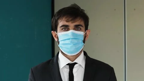 At work with mask - young manager wearing the mask stares at camera - indoor Stock Footage 142908535