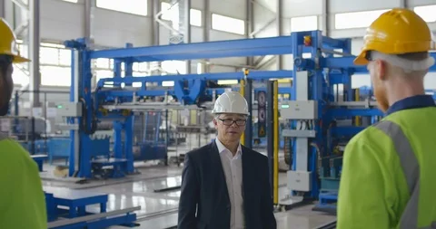 Work meeting at modern factory. Engineer or businessman in formal suit greets Stock Footage 121102177