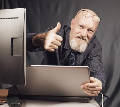 Work in the office, a cheerful elderly man with a gray beard in front of a Foto stock