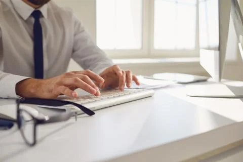 Work online. Busy faceless worker is typing at workplace using computer in Stock Photos