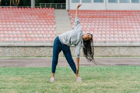 The work-out of the athletic afro-american girl doing exercises on the stadium Stock Photos