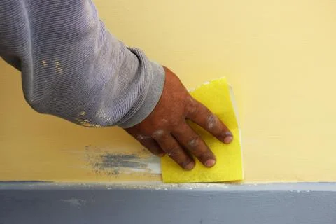 Work plasterer processes the wall of the house with sandpaper. Elimination of Stock Photos