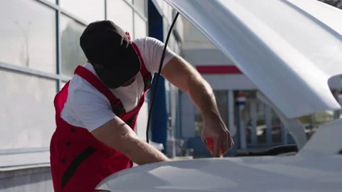The work process in a car service. Auto mechanic dressed in red work uniform Stock Footage 280030756
