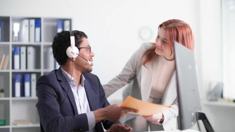 Work process, cute woman brings documents to african american colleague while Stock Footage 239759658