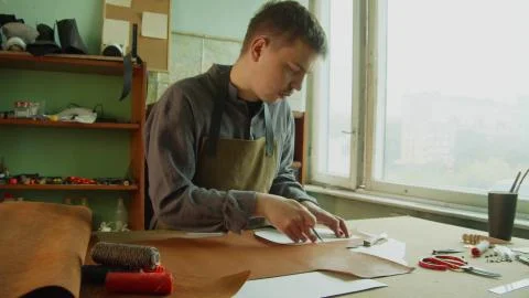 Work in progress. A leather craftsman outlines elements for cutting out a piece Stock Photos