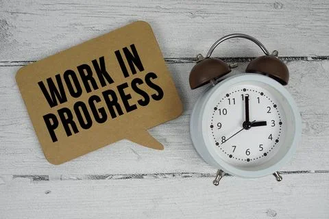 Work in progress text with alarm clock on wooden background Stock Photos