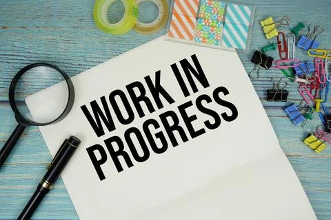 Work In Progress text written on notepad with magnifying glass flat lay on .. Foto stock