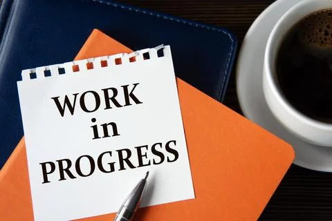 WORK IN PROGRESS - words on a white sheet of paper against the background o.. Stock Photos