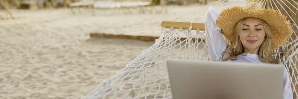Work remotely. Side view of a young happy female freelancer in a straw hat Stock Photos