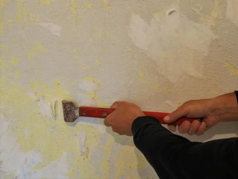 Work with a scraper to clean the remnants of wallpaper from the wall Stock Photos