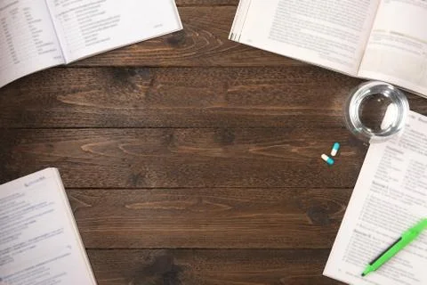 Work stress concept. Workspace desk with pharmaceutical pills, books, pen, pa Stock Photos
