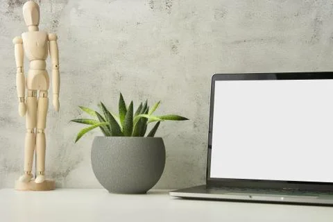 Work table with laptop with white clean screen, flower and wooden drawing figure Stock Photos