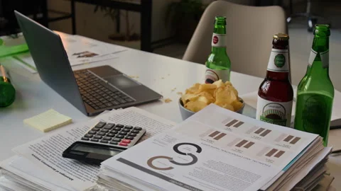 Work Table Showing Laptop, Documents, Calculator, Bowl of Chips, Beer Bottles Stock Footage 331528705