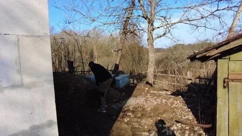 Work takes place in a rural area with trees and a building on a clear day while Stock-Footage 332563724
