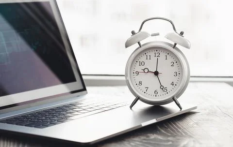 Work time concept. Home desktop with laptop, graph and alarm clock on desk Stock Photos