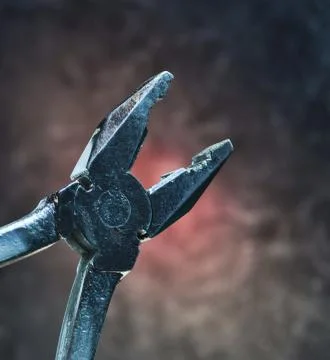Work tool pliers against the background of the concrete wall. Mystical red li 库存照片