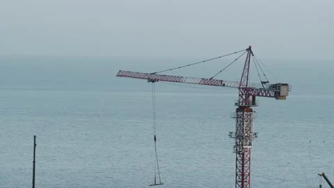 The work of the tower crane on the background of the sea surface. Construction o Stock Footage 233683240