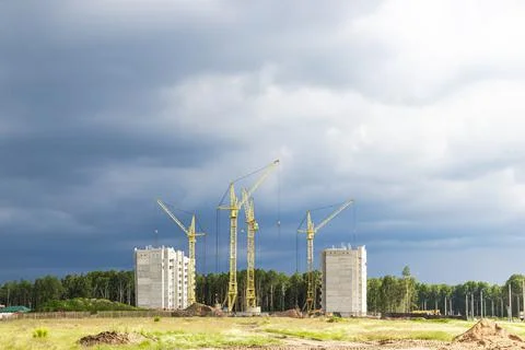 The work of tower cranes against the background of the sunset sky. Photos