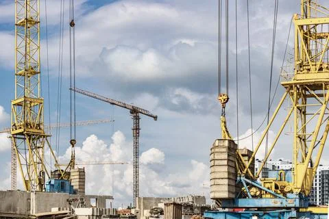 The work of tower cranes against the background of the sunset sky. Stock Photos