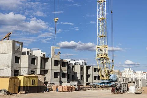 The work of tower cranes against the background of the sunset sky. 库存照片