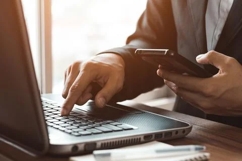 Work using mobile phone typing computer mobile chat laptop contact us at work Stock Photos