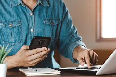Work using mobile phone typing computer mobile chat laptop contact us at work Stock Photos