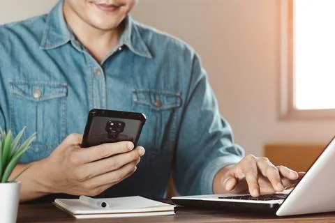 Work using mobile phone typing computer mobile chat laptop contact us at work Stock Photos