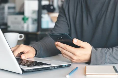 Work using mobile phone typing computer mobile chat laptop contact us at work Stock Photos