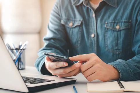 Work using mobile phone typing computer mobile chat laptop contact us at work Stock Photos