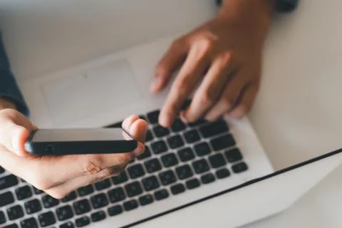 Work using mobile phone typing computer mobile chat laptop contact us at work Stock Photos