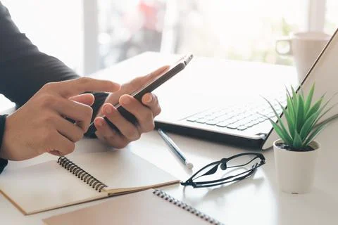 Work using mobile phone typing computer mobile chat laptop contact us at work Stock Photos