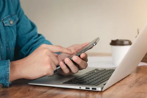 Work using mobile phone typing computer mobile chat laptop contact us at work Stock Photos