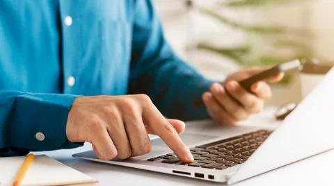 Work using mobile phone typing computer mobile chat laptop contact us at work Stock Photos