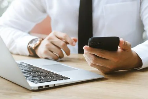 Work using mobile phone typing computer mobile chat laptop contact us at work Stock Photos